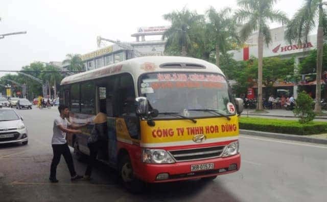 Xe buýt màu trắng chạy trên đường phố có cây xanh ở Thanh Hóa