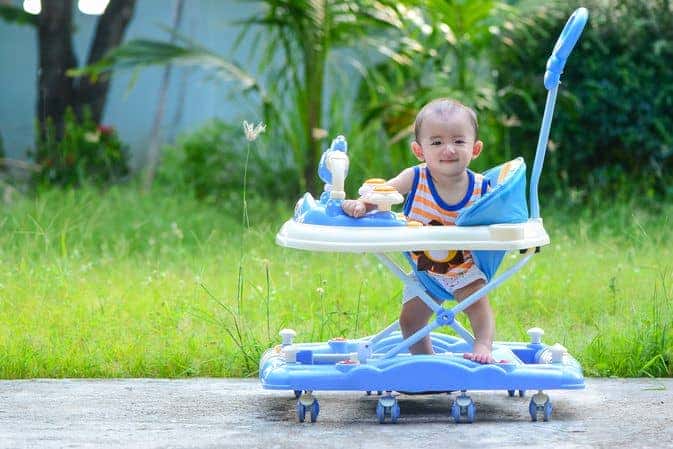 Bé đang tập đi trong xe tập đi tròn dưới sự giám sát của người lớn