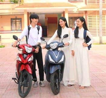 Học sinh lái xe số và xe ga 50cc trên đường, có mũ bảo hiểm