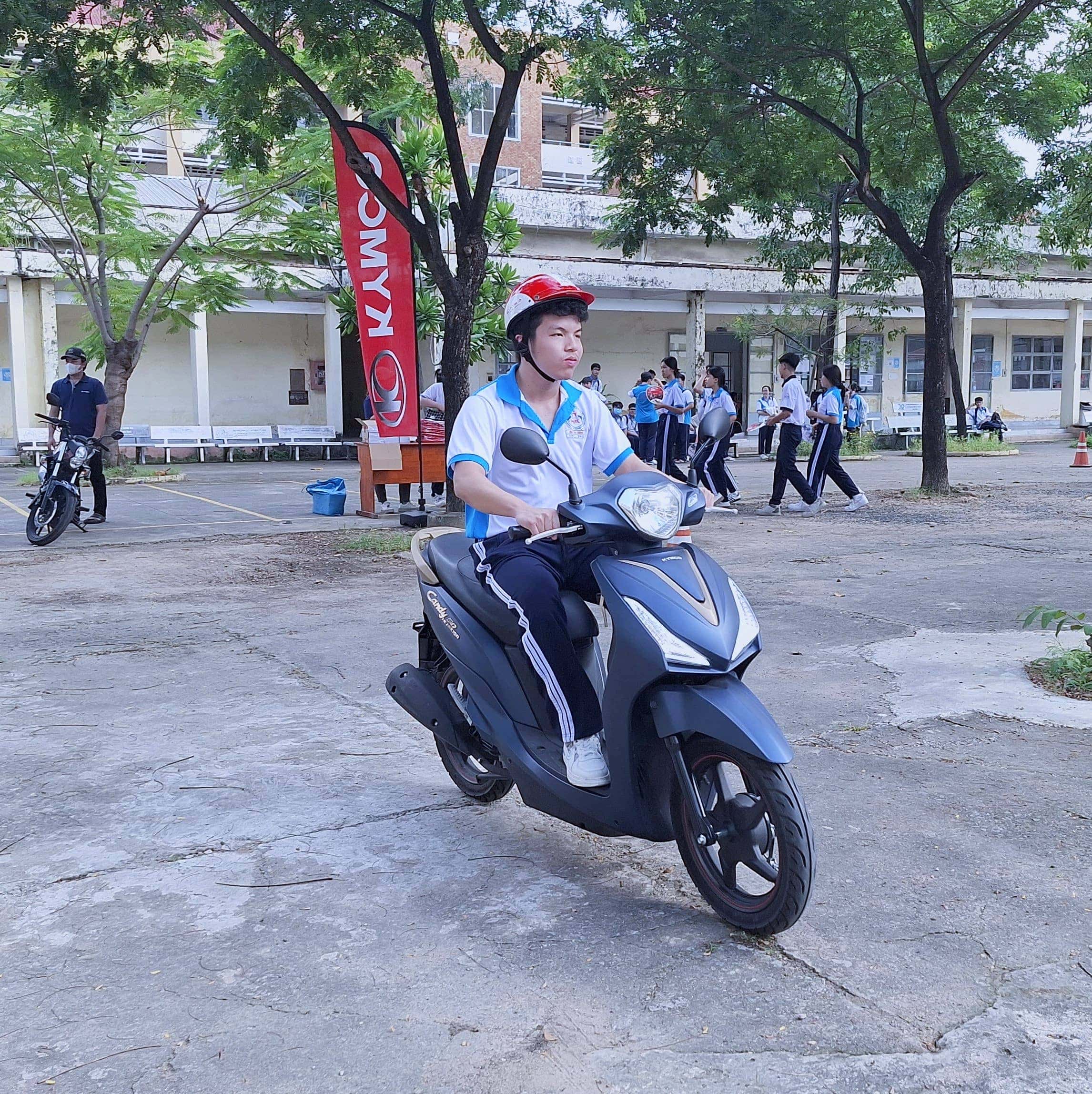 Học sinh nữ đang lái một chiếc xe tay ga 50cc màu trắng trên đường